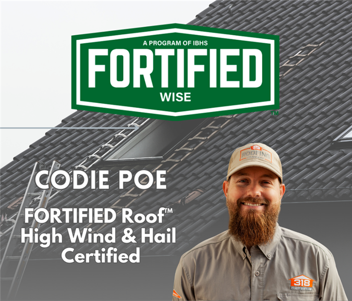 Codie Poe in front of a roof with Fortified Roofing logo behind him 