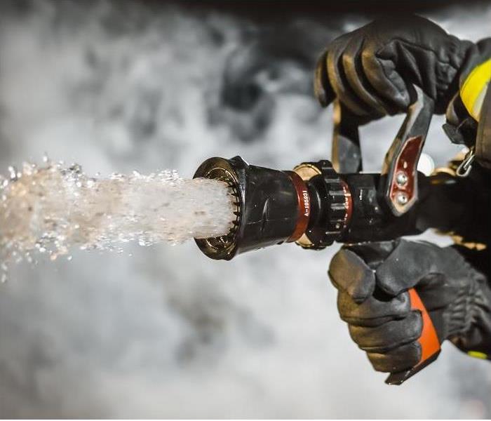 closeup of fireman's hand holding hose, water spraying from hose