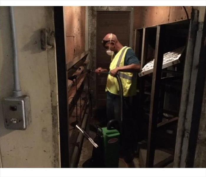 SERVPRO technician vacuuming soot from fire damaged building