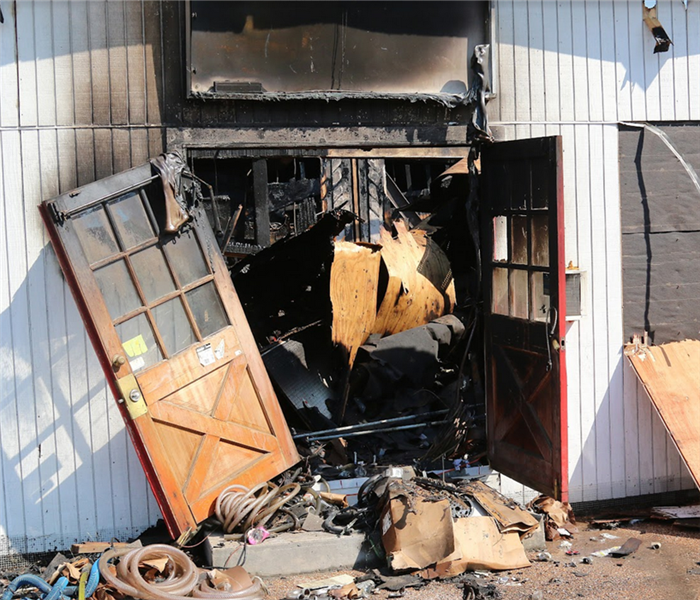 a fire damaged entrance of a store with soot covered doors and debris inside